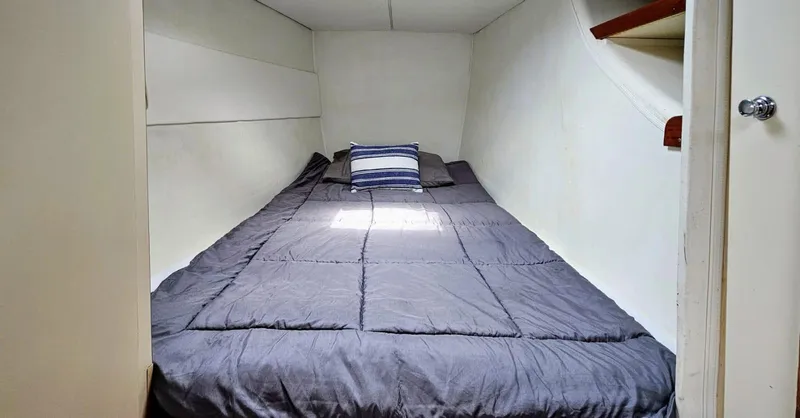  Yacht Photos Pics Cozy cabin bed inside a 1994 Lagoon 42 yacht, featuring a striped pillow.
