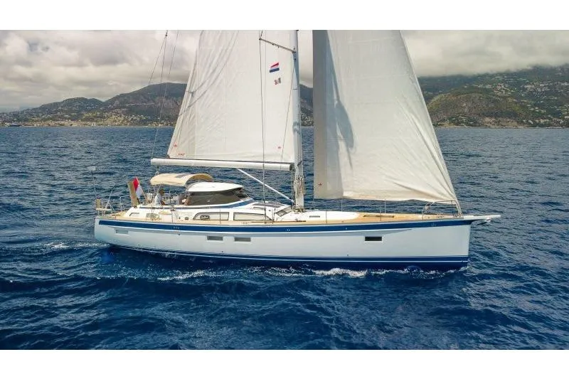  Yacht Photos Pics 2023 Hallberg-Rassy 50 sailing yacht on open sea with scenic mountain backdrop.