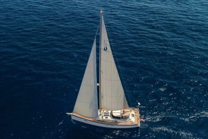  Yacht Photos Pics 2023 Hallberg-Rassy 50 sailing yacht on open sea, aerial view.
