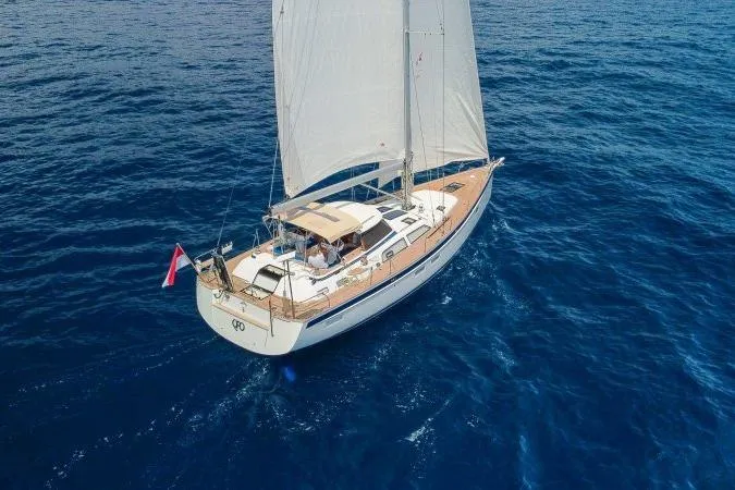  Yacht Photos Pics 2023 Hallberg-Rassy 50 sailboat cruising on open blue sea, aerial view.