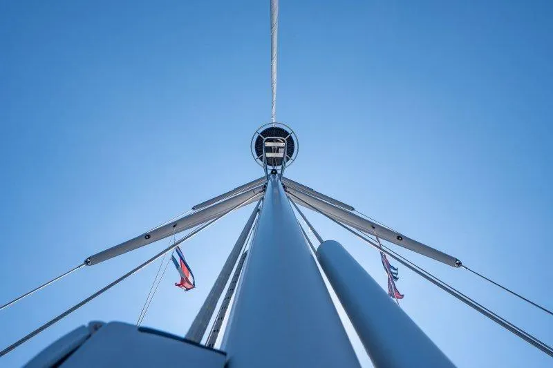  Yacht Photos Pics Looking up at the mast of a 2023 Hallberg-Rassy 50 sailboat against a clear blue sky.