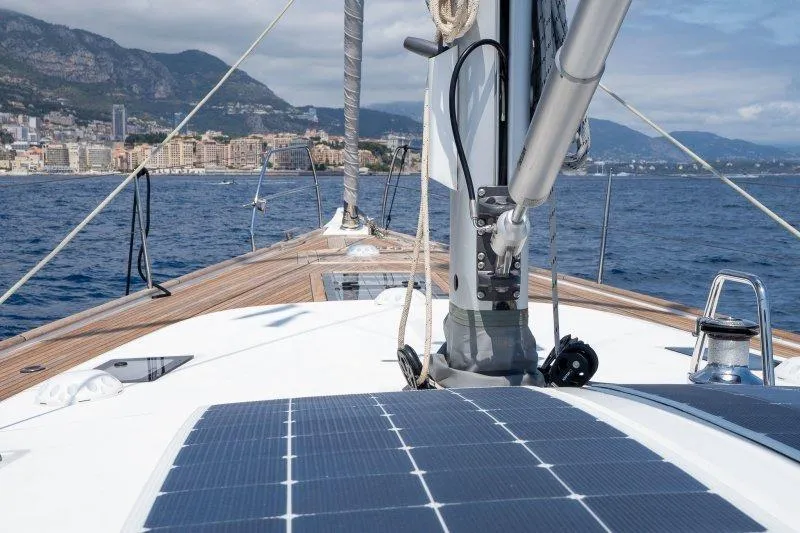  Yacht Photos Pics 2023 Hallberg-Rassy 50 yacht deck with solar panels, sailing near coastal city.