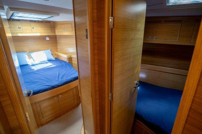  Yacht Photos Pics Luxurious 2023 Hallberg-Rassy 50 yacht interior with cozy wooden cabins and blue bedding.