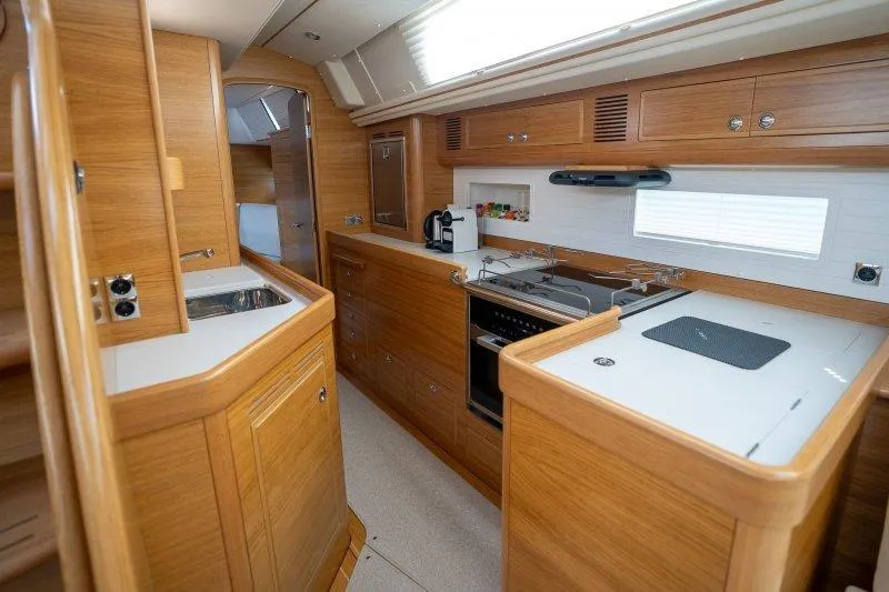  Yacht Photos Pics Luxurious 2023 Hallberg-Rassy 50 yacht interior with modern kitchen and wooden cabinetry.