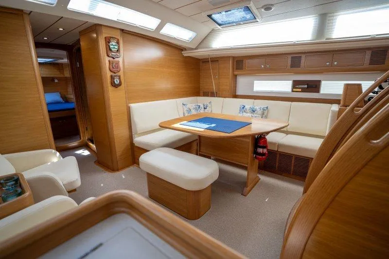  Yacht Photos Pics Luxurious interior of 2023 Hallberg-Rassy 50 yacht with elegant wood finish and seating area.