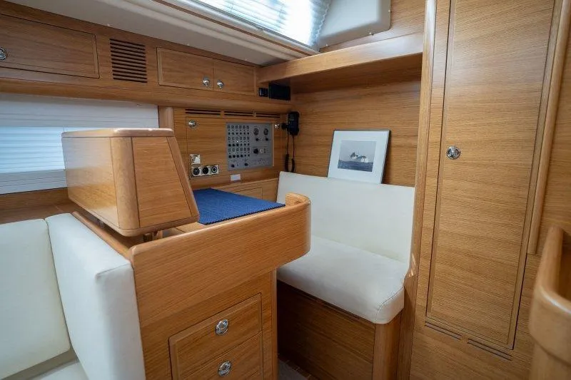  Yacht Photos Pics 2023 Hallberg-Rassy 50 yacht interior with wooden cabinetry and navigation station.