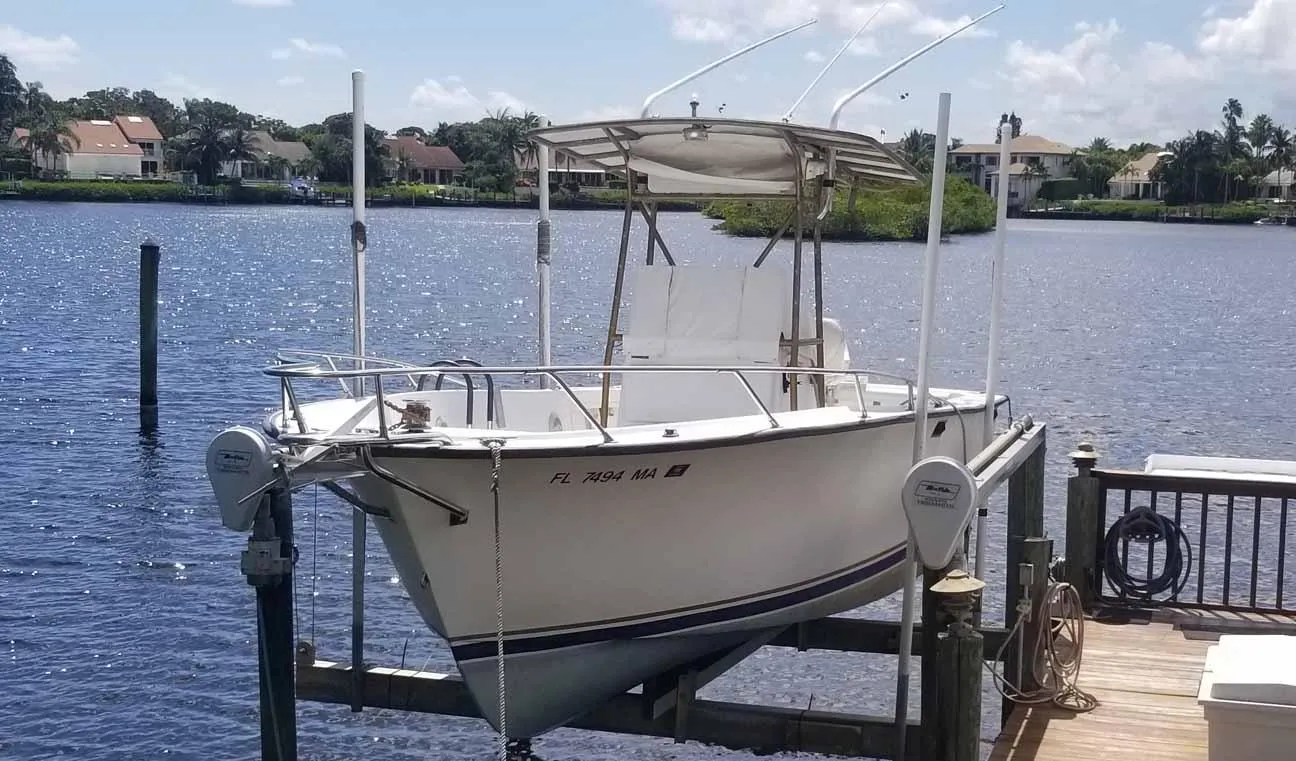 1977 Pace Wahoo boat docked on a sunny waterfront with houses in the background.