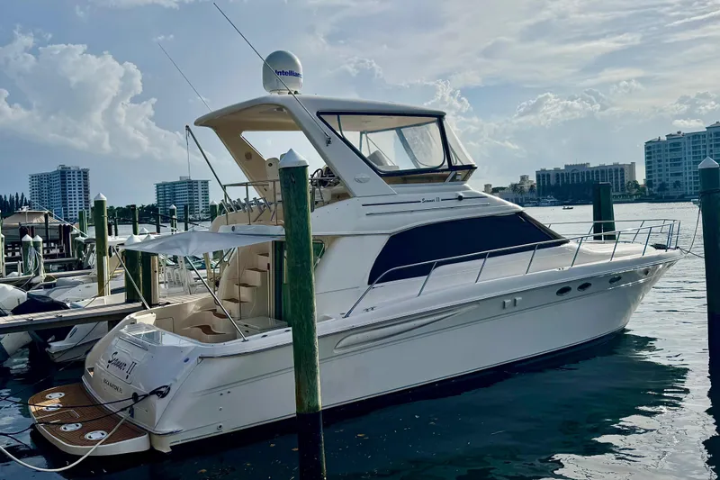 Scanner II Yacht Photos Pics 1998 Sea Ray 480 Sedan Bridge yacht docked at marina, with city skyline in background.
