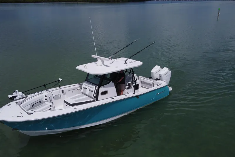  Yacht Photos Pics 2024 Blackfin 332 CC boat on calm water, featuring dual engines and fishing rods.