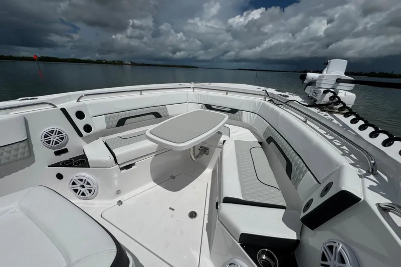  Yacht Photos Pics 2024 Blackfin 332 CC boat interior with seating and table, under cloudy sky.