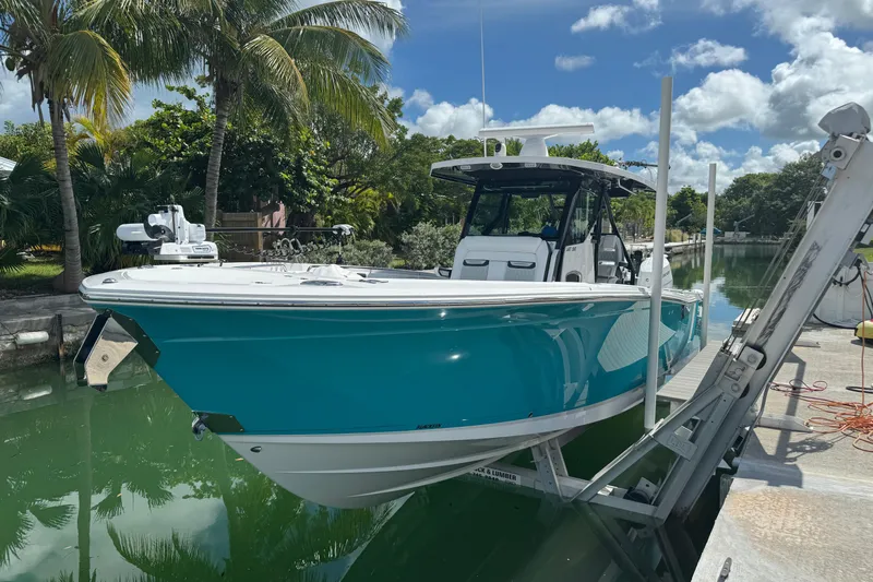  Yacht Photos Pics 2024 Blackfin 332 CC boat docked on a sunny day, surrounded by lush greenery.