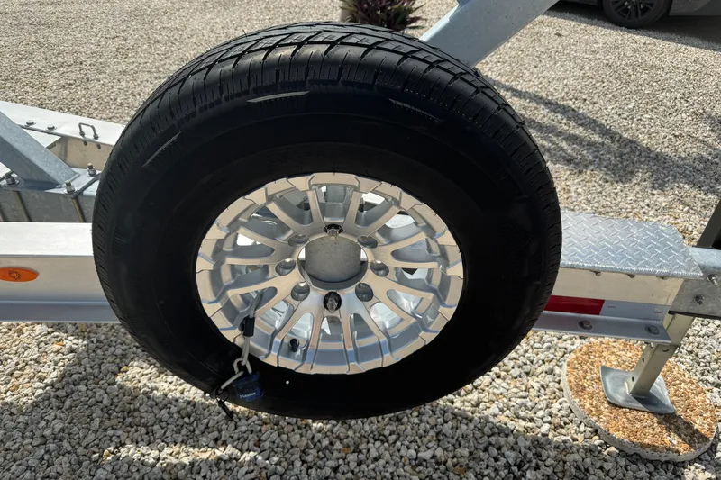  Yacht Photos Pics Trailer wheel on gravel, part of 2024 Blackfin 332 CC boat trailer.
