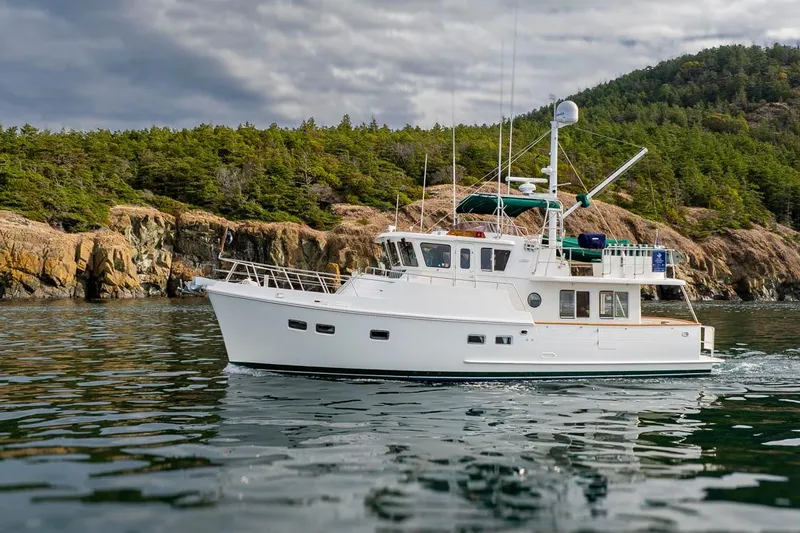 Forever Young Yacht Photos Pics White Selene 43 yacht cruising near rocky coastline, 2009 model, under cloudy sky.