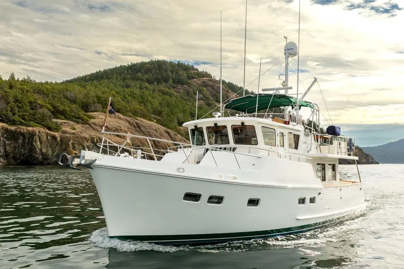 Forever Young Yacht Photos Pics 2009 Selene 43 yacht cruising near scenic rocky coastline under cloudy sky.