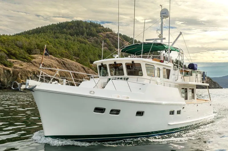 Forever Young Yacht Photos Pics 2009 Selene 43 yacht cruising near a forested coastline under a cloudy sky.