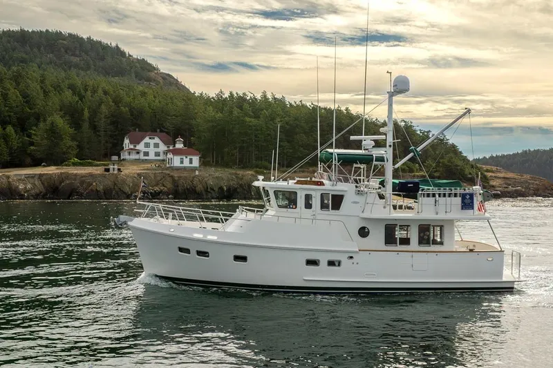 Forever Young Yacht Photos Pics 2009 Selene 43 yacht cruising near a scenic coastal landscape with a house and trees.