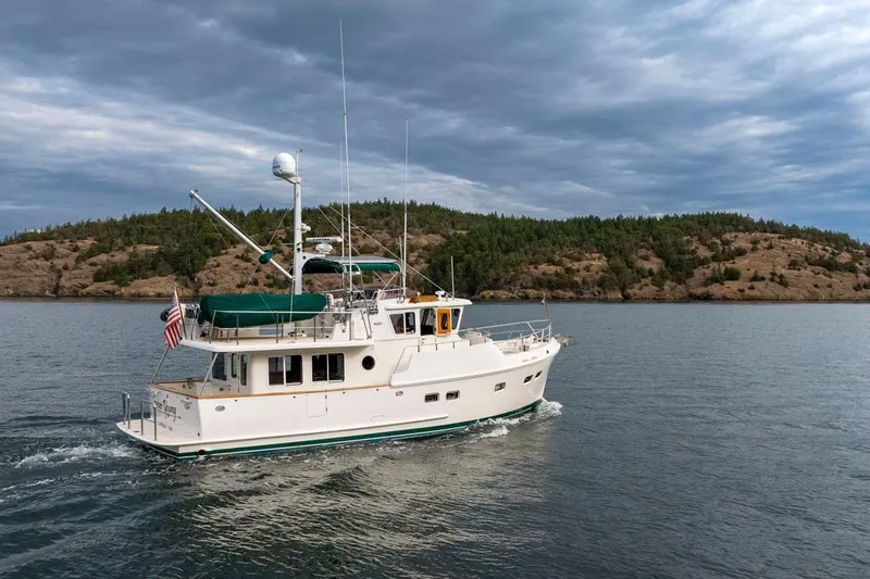 Forever Young Yacht Photos Pics 2009 Selene 43 yacht cruising near forested island under cloudy sky.