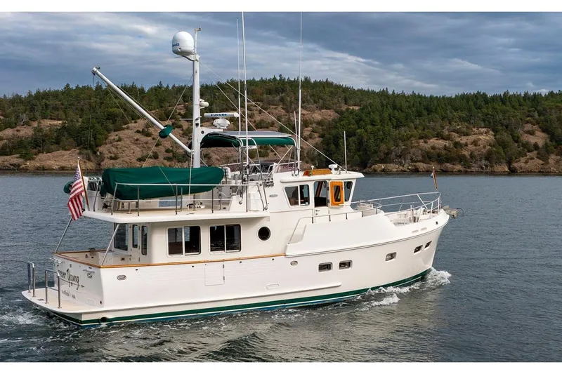 Forever Young Yacht Photos Pics 2009 Selene 43 yacht cruising near a forested shoreline under a cloudy sky.