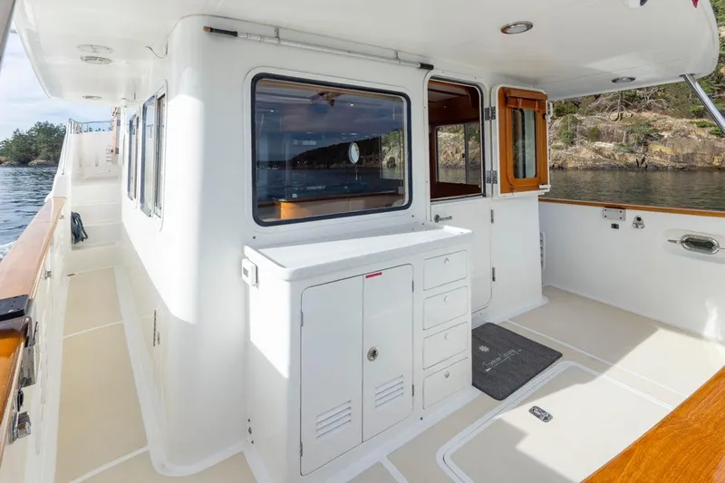 Forever Young Yacht Photos Pics 2009 Selene 43 yacht deck with white cabinetry and wooden accents, near scenic shoreline.