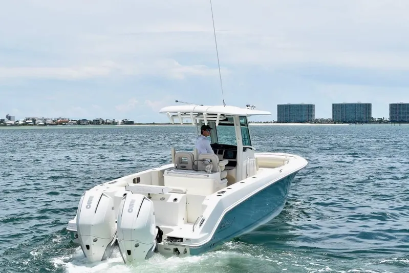  Yacht Photos Pics 2023 Boston Whaler 280 Outrage boat cruising on open water near coastal buildings.