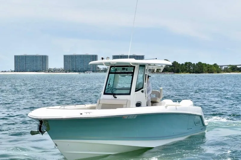  Yacht Photos Pics 2023 Boston Whaler 280 Outrage boat cruising on open water near coastal buildings.