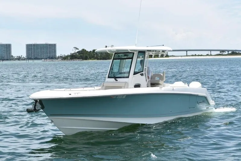  Yacht Photos Pics 2023 Boston Whaler 280 Outrage boat cruising on open water, with coastal buildings in background.