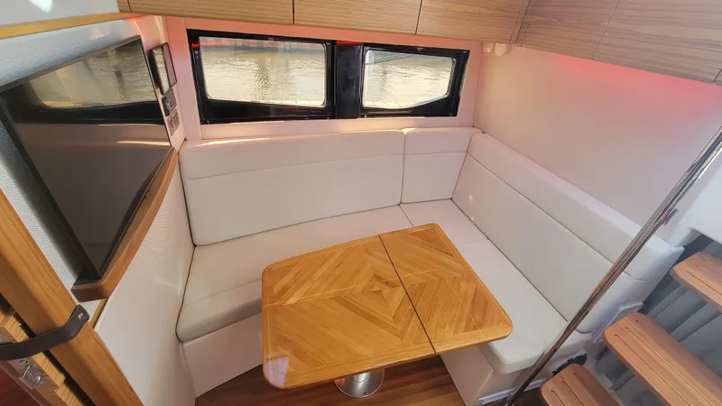  Yacht Photos Pics Interior of 2021 Boston Whaler 405 Conquest with cozy seating and wooden table.