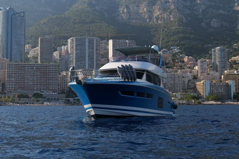 Grace Yacht Photos Pics Prestige 620 yacht, 2013 model, cruising near a city skyline with mountains.