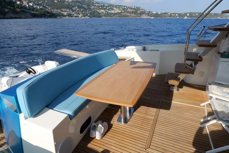 Grace Yacht Photos Pics Prestige 620 yacht deck with seating and table, overlooking scenic coastal view.