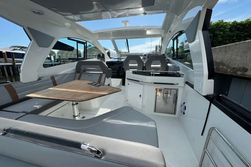  Yacht Photos Pics 2022 Beneteau Gran Turismo 32 interior with seating, table, and kitchenette under a sunny sky.