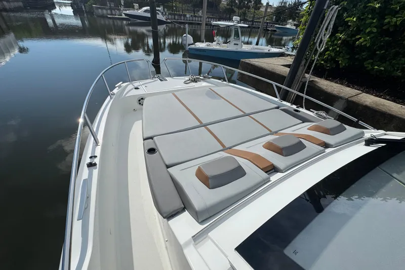  Yacht Photos Pics 2022 Beneteau Gran Turismo 32 yacht with spacious sunbathing deck in a serene marina setting.