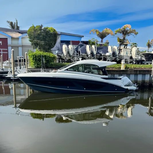  Yacht Photos Pics 2022 Beneteau Gran Turismo 32 yacht docked in a marina, reflecting on calm water.