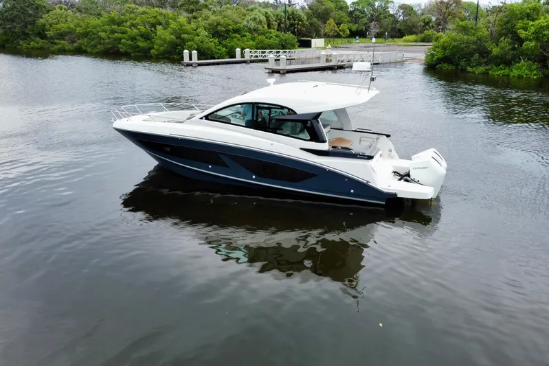  Yacht Photos Pics 2022 Beneteau Gran Turismo 32 yacht on calm water, surrounded by lush greenery.