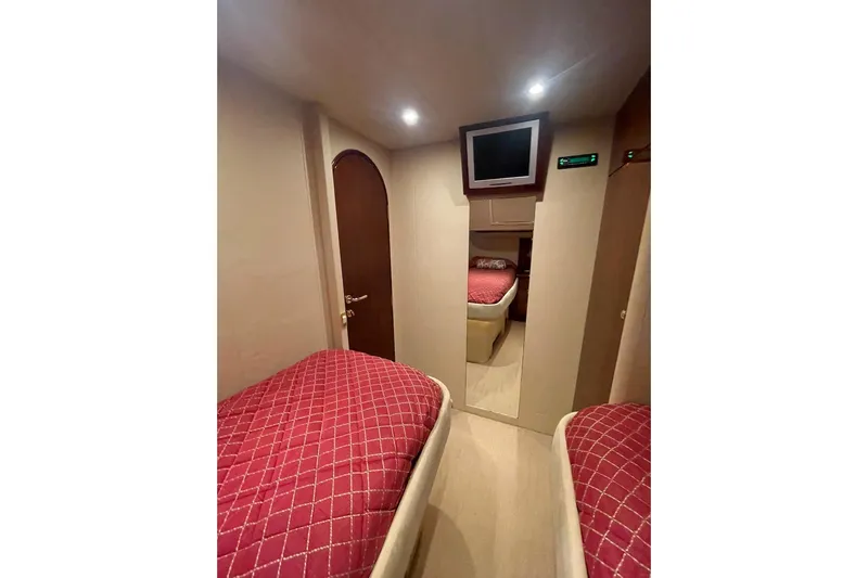 Passe Ports V Yacht Photos Pics 2004 Neptunus 56 Flybridge cabin with twin beds, red bedding, and wall-mounted TV.