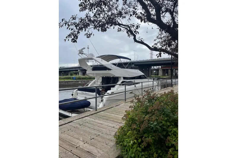 Passe Ports V Yacht Photos Pics 2004 Neptunus 56 Flybridge yacht docked by a wooden walkway, under a cloudy sky.