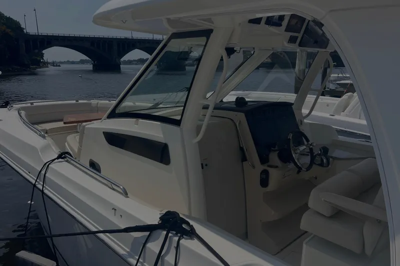  Yacht Photos Pics 2020 Boston Whaler 350 Realm boat interior with steering wheel, docked near a bridge.