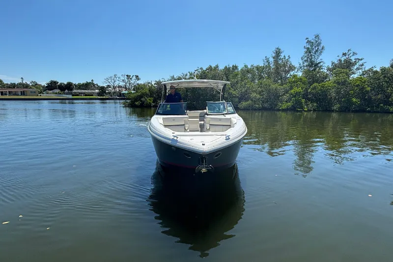  Yacht Photos Pics 2022 Cobalt 30SC boat on calm water, surrounded by lush greenery.