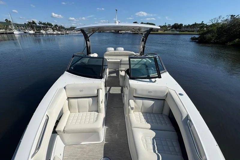  Yacht Photos Pics 2022 Cobalt 30SC boat with white seating, cruising on a calm river under a clear sky.