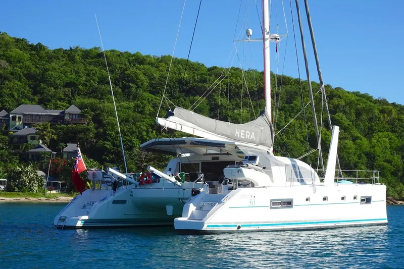 Hera Yacht Photos Pics 2008 Catana 50 catamaran anchored near lush green shoreline.