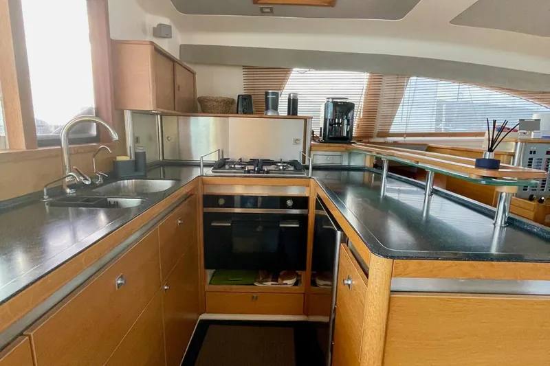 Hera Yacht Photos Pics Modern kitchen interior on a 2008 Catana 50 yacht, featuring sleek countertops and wooden cabinetry.