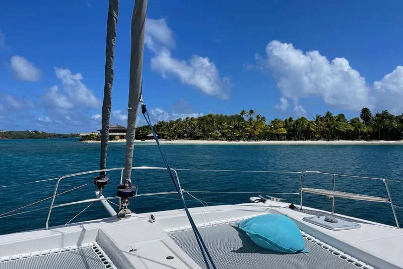 Hera Yacht Photos Pics Catana 50 catamaran sailing near tropical island, clear blue sky, and ocean, 2008 model.