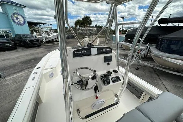 2024 Avenger AV26 boat interior with steering console, docked under cloudy sky.