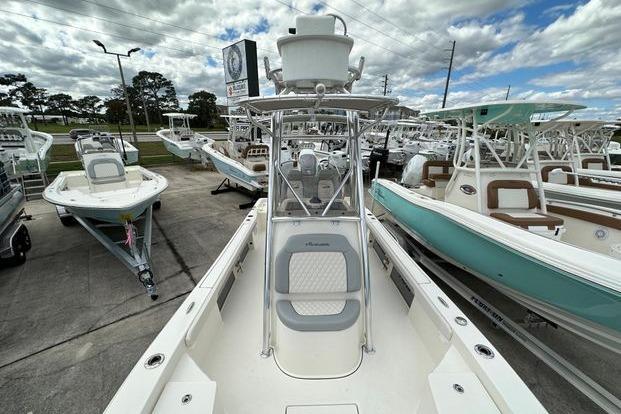 2024 Avenger AV26 boat displayed in a dealership, surrounded by other boats under a cloudy sky.