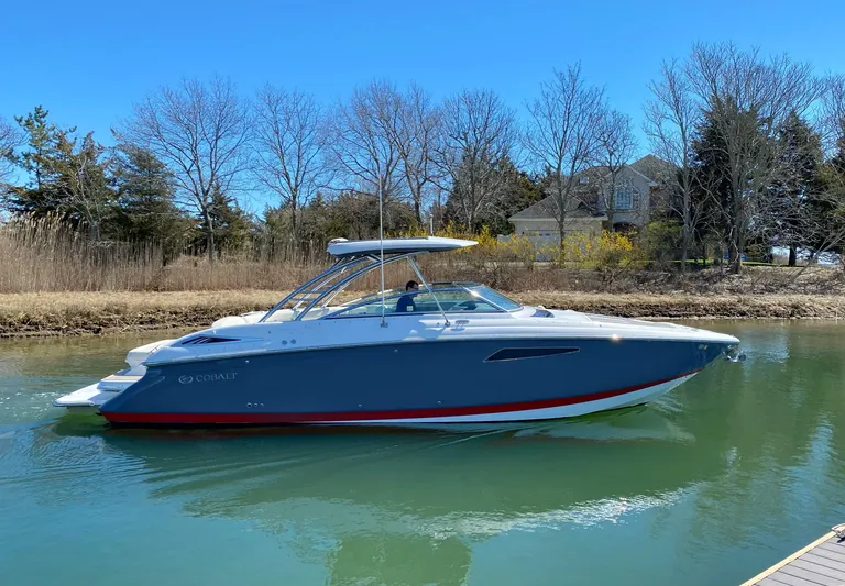  Yacht Photos Pics 2018 Cobalt R35 boat on calm water near a wooded shoreline.
