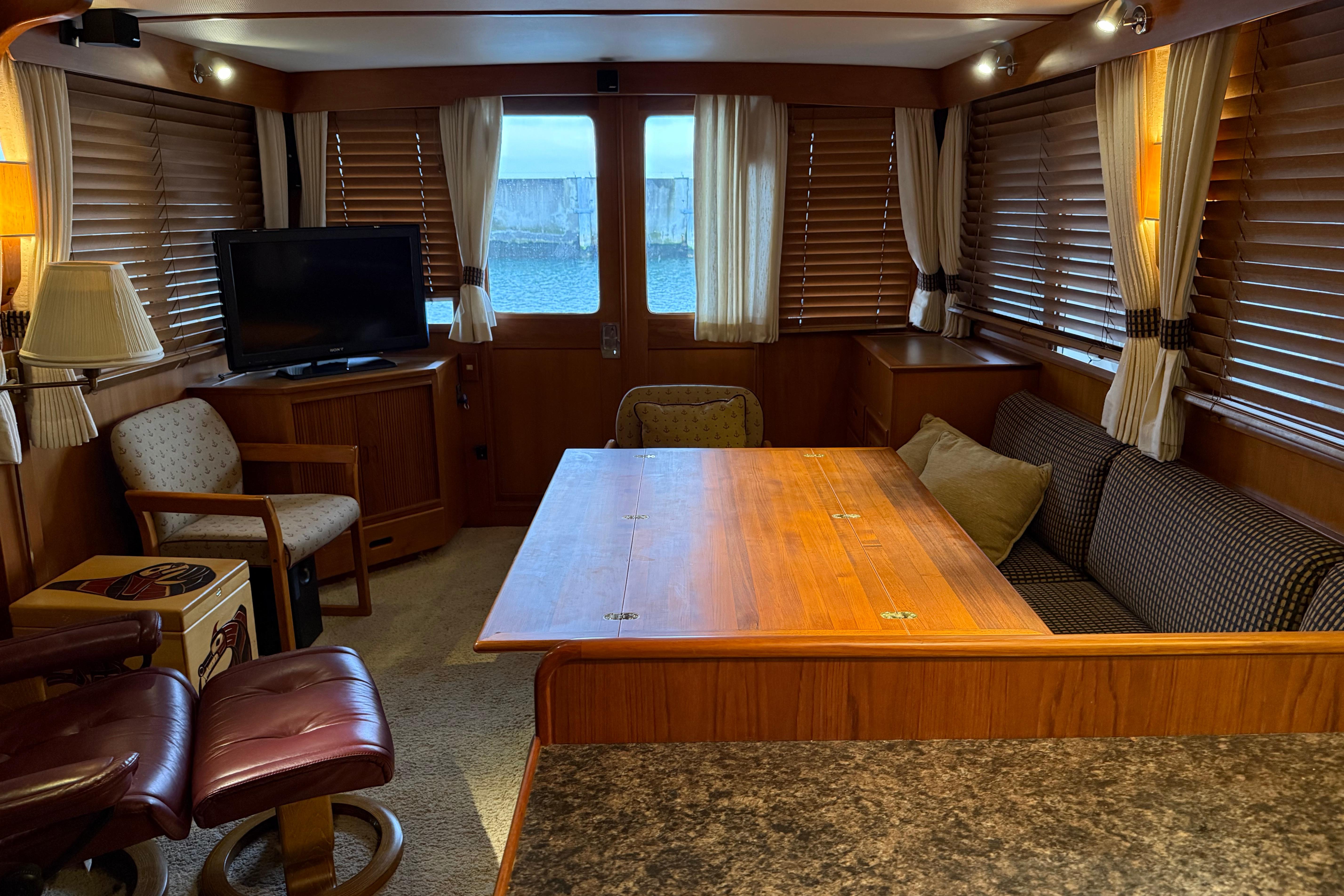 Luxurious 1988 Fleming Pilothouse interior with wood accents, cozy seating, and a TV.