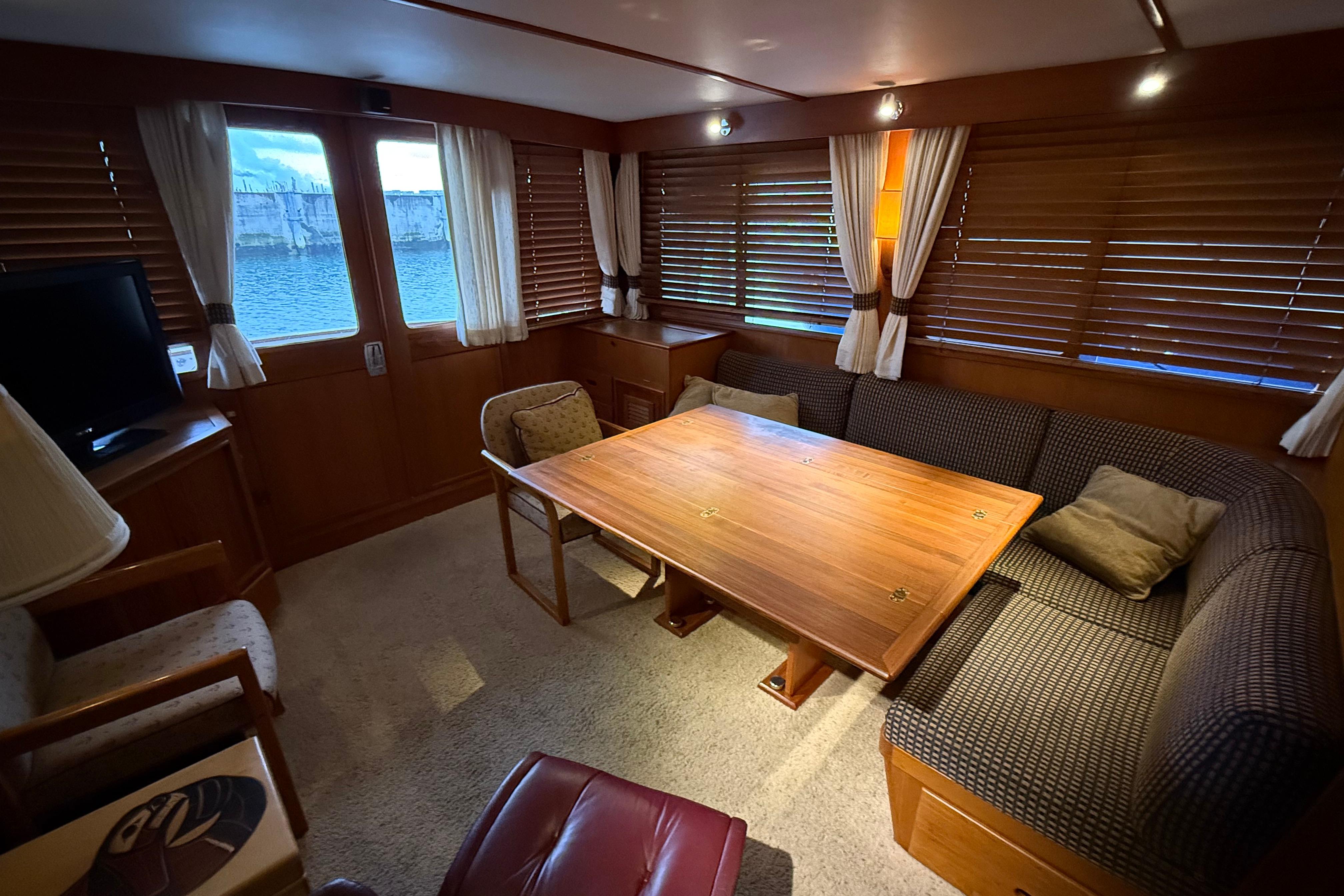 1988 Fleming Pilothouse interior with wooden table, cozy seating, and window views.