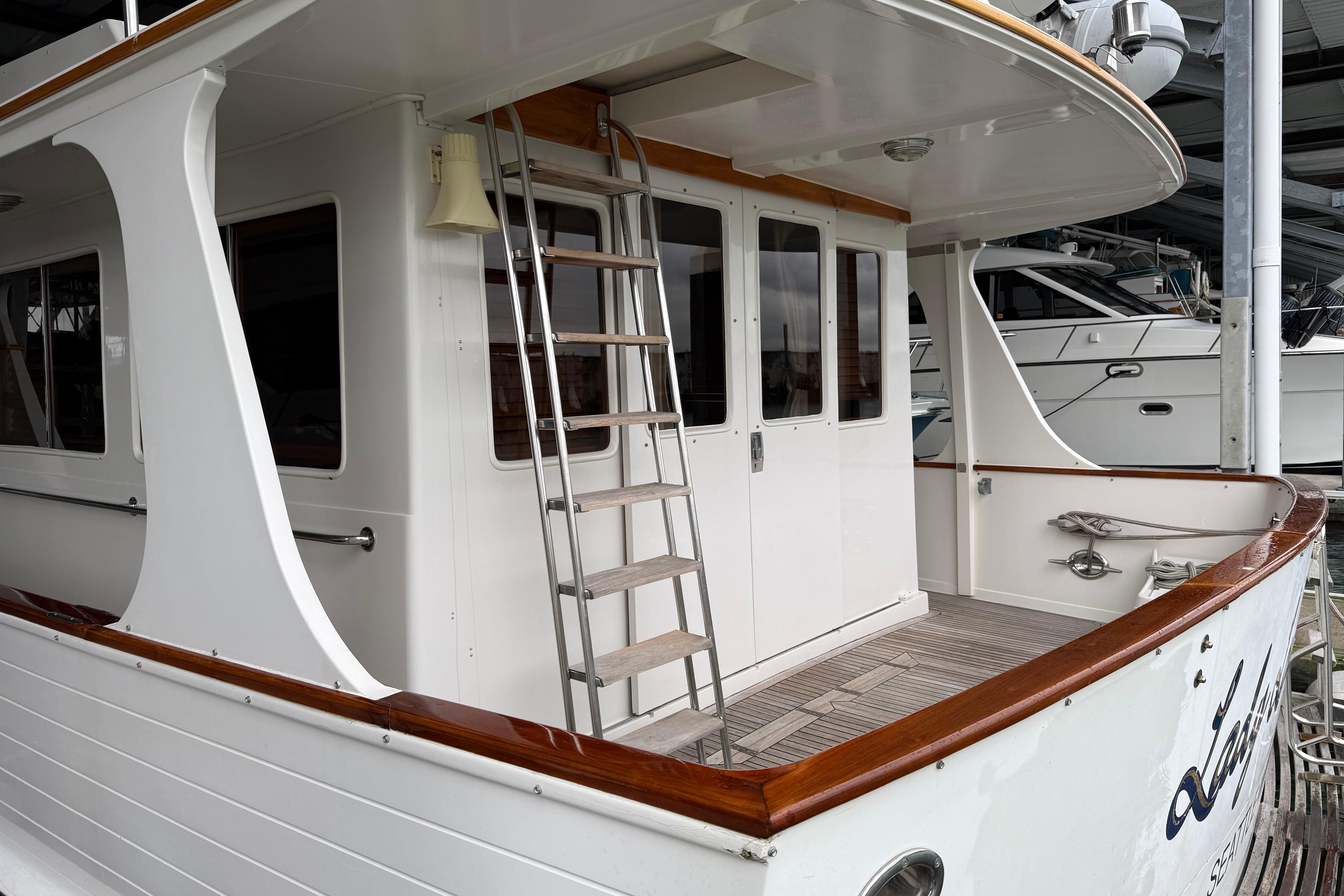 1988 Fleming Pilothouse yacht with wooden deck and ladder, docked in a marina.