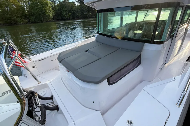 Raven Yacht Photos Pics 2021 Axopar 37 XC CROSS CABIN boat with cushioned seating, docked by a serene lake.