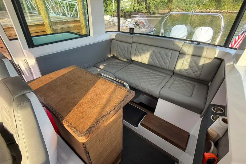 Raven Yacht Photos Pics Interior of 2021 Axopar 37 XC CROSS CABIN with gray seating and wooden table.
