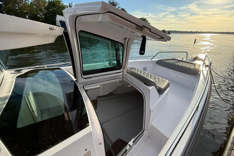 Raven Yacht Photos Pics 2021 Axopar 37 XC CROSS CABIN boat with open cabin door, docked by a serene lake.